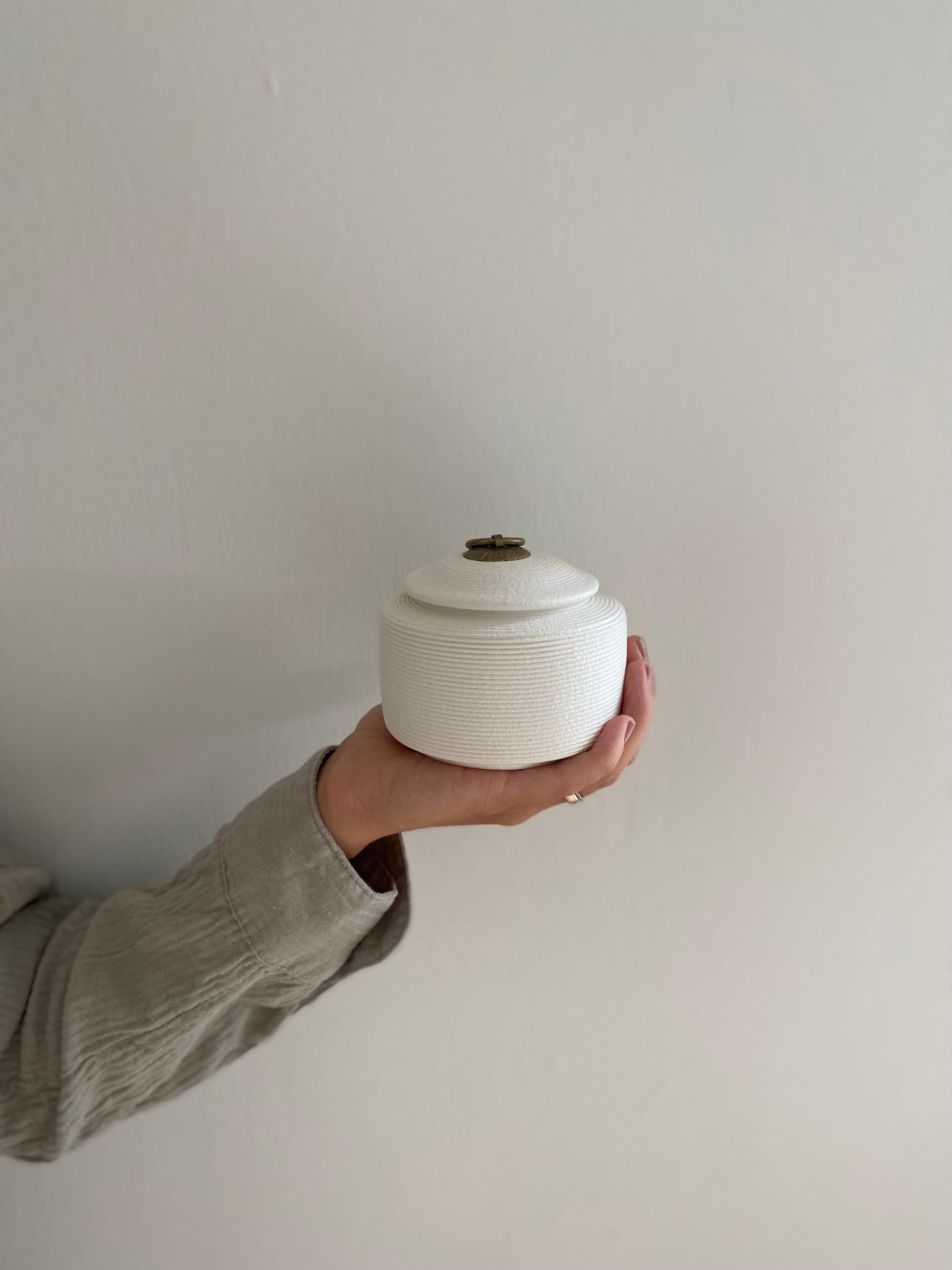 kleine witte oosterse keramische urn voor mens en dier in hand