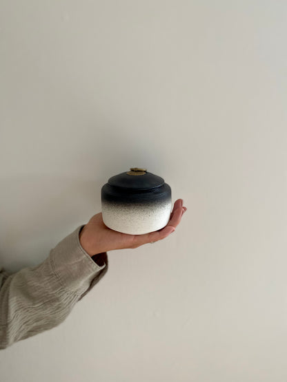 kleine zwart witte oosterse urn voor mens en dier in hand